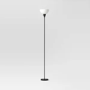 Torchiere floor lamp tucked in a corner behind a sofa